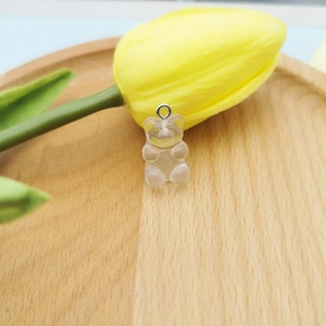 Detailed close-up of a translucent resin gummy bear pendant with a metal ring on wood