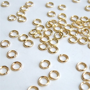 Anneaux de jonction dorés pour création de bijoux DIY sur fond blanc épuré