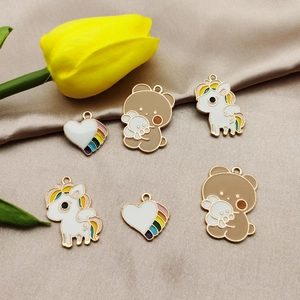 DIY cartoon pendants with bear, unicorn, and rainbow heart charms on silk background
