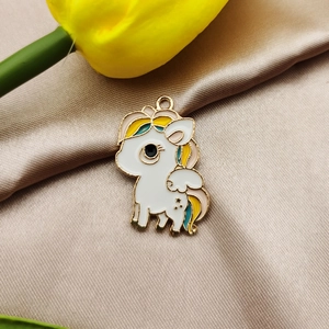 Macro shot of colorful unicorn charm with gold plating on elegant champagne satin fabric