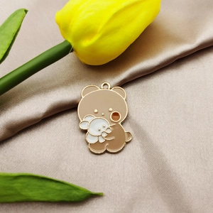 Macro detail of alloy bear and rabbit pendant on silk fabric with yellow tulip
