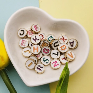 DIY colorful alphabet enamel charms in gold alloy on a white ceramic heart plate