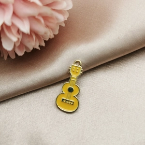 Detailed macro view of yellow guitar enamel pendant with gold trim on satin