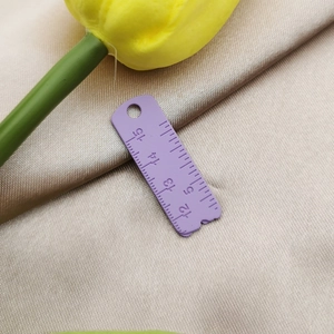 Close-up of a purple alloy ruler pendant with clear scales for jewelry DIY crafts
