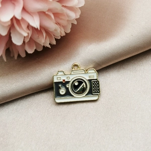 Detail of vintage camera alloy pendant in white and black enamel with gold metallic finish