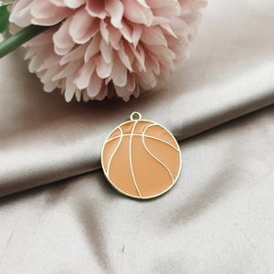 Detailed view of an orange basketball charm with gold metal lines on champagne satin