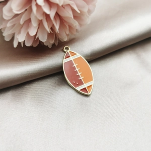 Detail of rugby-shaped enamel alloy pendant with golden edges on satin fabric background