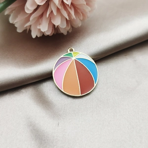 Detail of a colorful round enamel beach ball pendant on soft silk fabric background