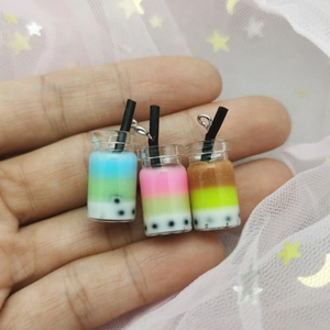 Three miniature resin bubble tea pendants in pastel colors held in hand for size comparison