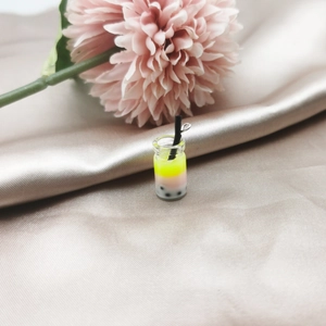 Macro detail of mini bubble tea pendant with yellow gradient liquid and metal hook