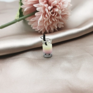 Macro shot of miniature 3-layer bubble tea charm with black pearls on silk fabric