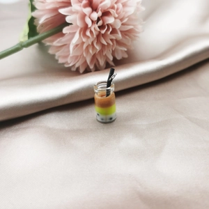 Macro detail of miniature bubble tea charms on satin fabric for DIY jewelry making