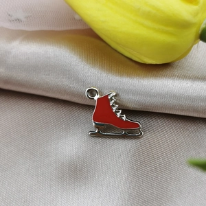 Detalle macro del colgante de patín de hielo de esmalte rojo con cuchilla plateada