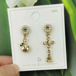 Gold Chinese knot and lucky bag earrings with pearls and metallic tassels on a card