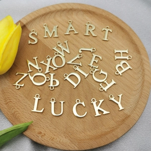 Pendentifs alphabet en alliage doré pour bijoux DIY sur un plateau en bois