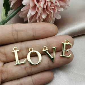 Pendentifs lettres LOVE dorées en main pour bijoux DIY avec fond floral élégant