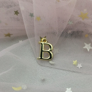 Vue macro d'un pendentif lettre B doré sur un fond de tulle rose rêveur à paillettes