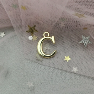 Vue macro détaillée d'un pendentif lettre C dorée avec fond de paillettes en étoile