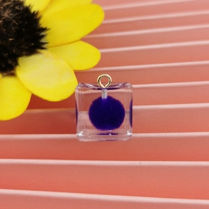 Dettaglio pendente cubo in resina trasparente con pallina viola e gancio dorato