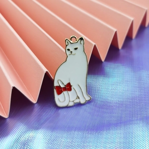 Detail van een witte emaille kattenhanger met rode strik en goudkleurige rand