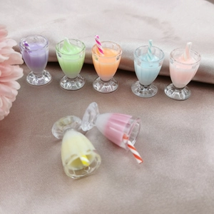 Miniature colorful milkshake bottle charms with striped straws on satin background