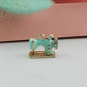 Dettaglio macro del ciondolo a forma di macchina da cucire con smalto menta e strass bianchi