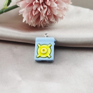 Détail du pendentif radio en résine bleu clair avec détails jaunes et anneau argenté