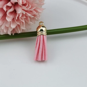 Macro view of pink suede tassel charm with elegant gold metal cap on white background