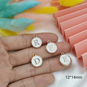 Golden round alphabet charm with white enamel and uppercase letters for DIY jewelry