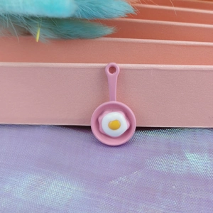 Detailed close-up of a pink alloy frying pan pendant with a resin egg for DIY jewelry