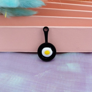 Macro shot of miniature frying pan charm with resin fried egg detail for DIY jewelry