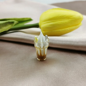 Macro detail of miniature resin ice cream pendant with cream topping and yellow straw