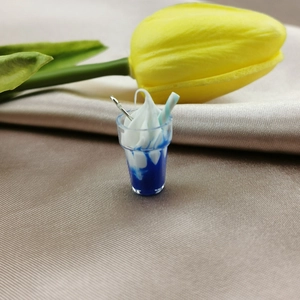 Macro detail of a mini blue ice cream cup pendant with resin cream and striped straw