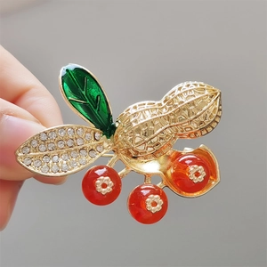 Élégante broche cacahuète dorée avec perles rouges, feuilles vertes et strass brillants