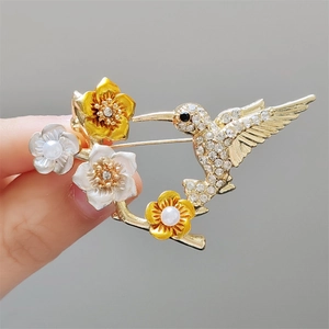 Détails de la broche colibri avec cristaux étincelants et fleurs colorées