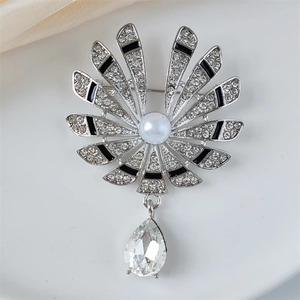 Macro shot of sparkling rhinestone flower brooch with central pearl and hanging crystal