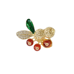 Élégante broche cacahuète dorée avec feuilles de strass et accents de perles rouges