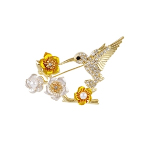 Broche colibri élégante avec strass brillants et perles blanches sur pétales de fleurs