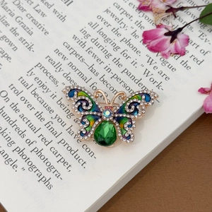 Bunte Emaille-Schmetterling-Brosche mit grünem Kristall und Strass auf einem Buch