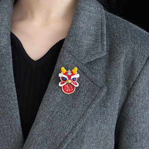 Red traditional Chinese dancing lion brooch with double joy character on gray coat