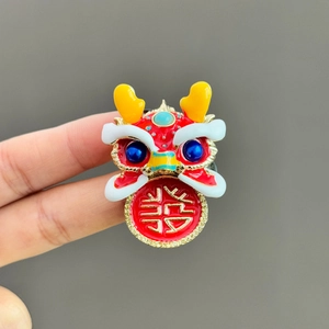 Detail of a red lion dance brooch featuring enamel craftsmanship and a lucky Xi character