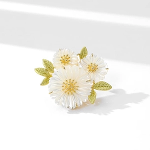 Elegant daisy flower brooch with white petals, golden stamens and green leaves
