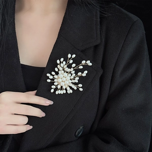 Elegant pearl fireworks brooch with gold metal wire on a black wool coat
