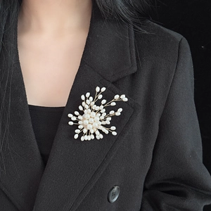 Elegant gold pearl firework starburst brooch pinned on a black luxury suit jacket lapel