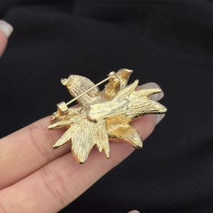 Close-up of the golden flower brooch back showing the detailed pin clasp and metal texture