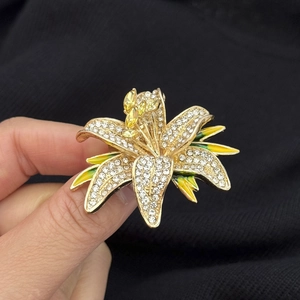 Luxury lily flower brooch with white crystals and enamel petals on black fabric