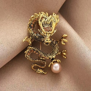 Spilla a forma di dragone dorato con strass e perla viola su sfondo di seta elegante