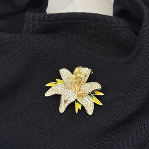Luxury lily flower brooch with white crystals and yellow gems on black fabric
