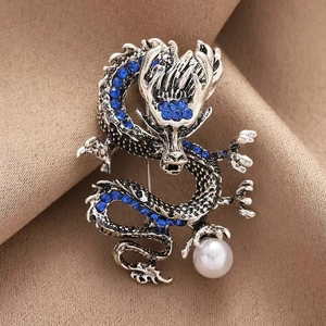 Spilla drago cinese argento con cristalli blu e perla su fondo di tessuto marrone