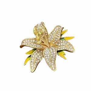 Close-up of lily flower brooch with clear crystals and yellow enamel detailing